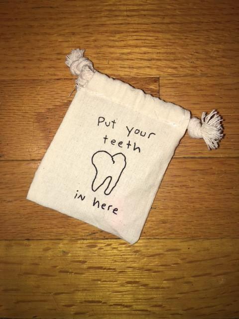 Small canvas pouch with handwritten text that says “Put your teeth in here”.