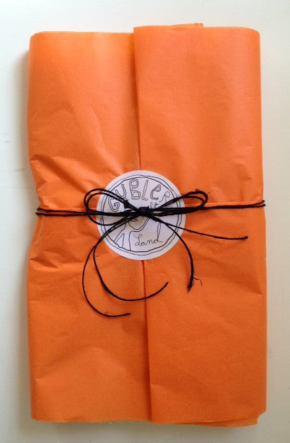 Orange tissue paper wrapped in black twine with Gublerland logo in center.