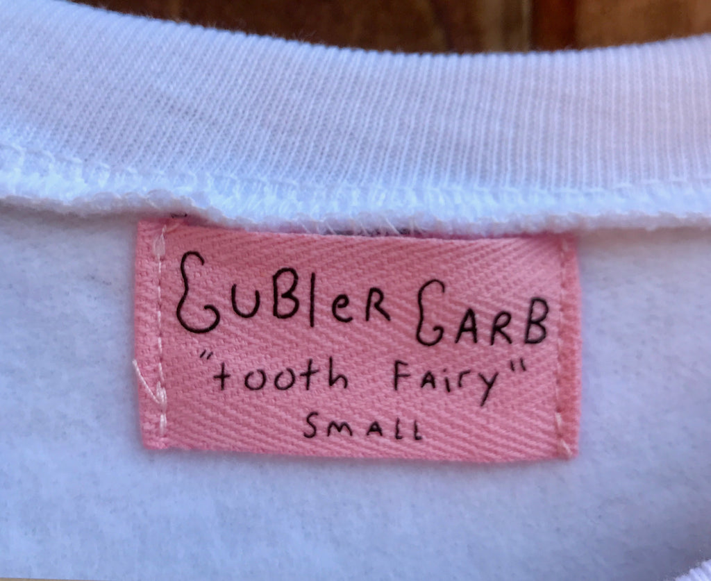 Pink, handwritten sweatshirt tag that says “Gubler Garb tooth fairy Small”.