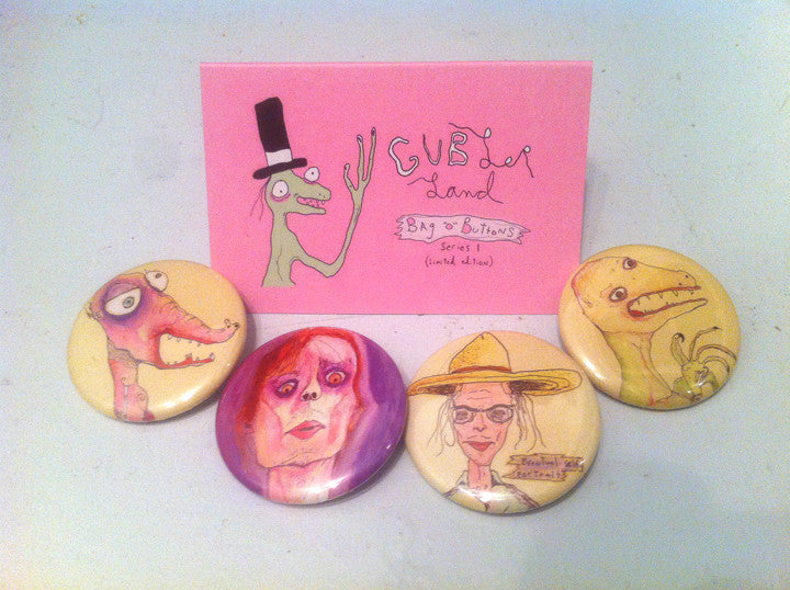 Four buttons with Gubler paintings on them. Card in background with "Gublerland Bag-O-Buttons" written on it.