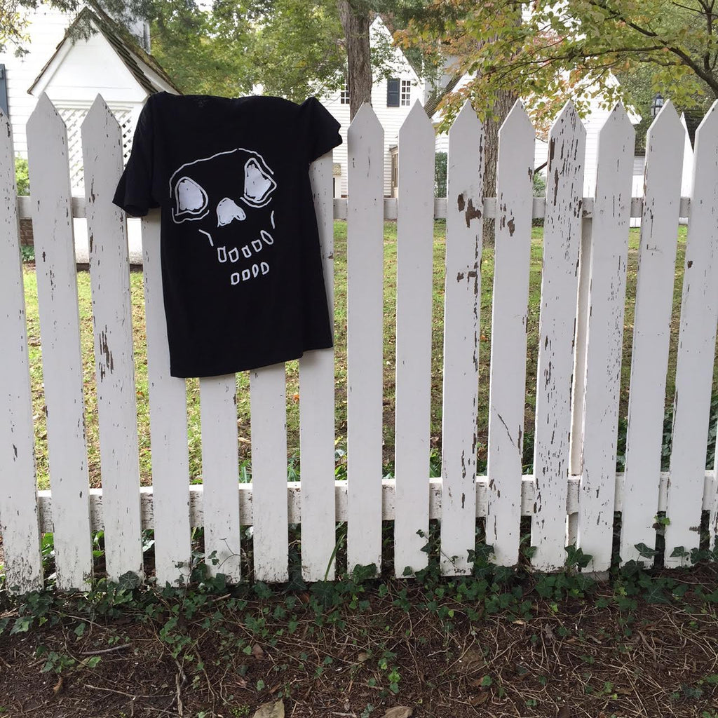  Hand-drawn skeleton on white t-shirt hanging on picket fence.