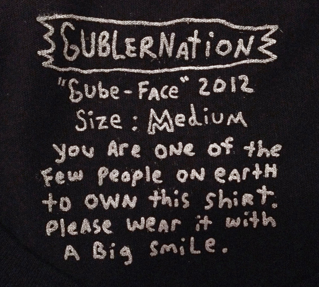 Hand-drawn label that says "Gublernation Gube-face 2012 size: Medium You are on of the few people on earth to own this shirt. please wear it with a big smile."