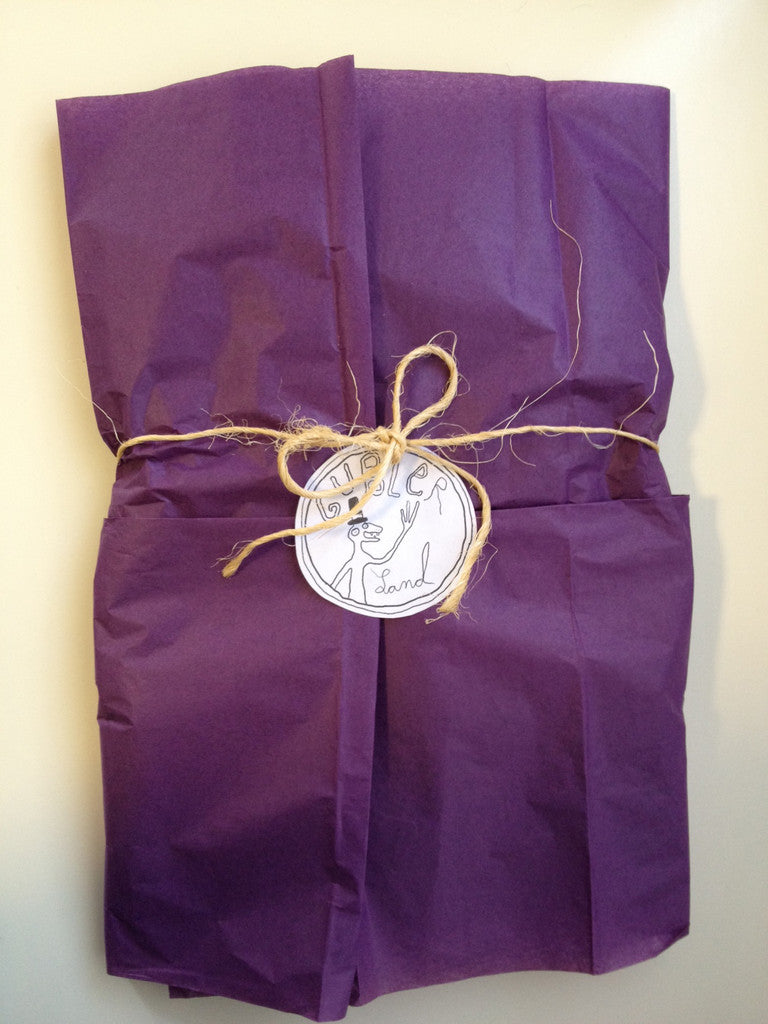 Purple tissue paper wrapped in brown twine with Gublerland logo in center.